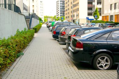 Şehir caddesi boyunca uzun bir sıra modern araba park ediyor. Kentsel ulaşım altyapısı, konut bölgesinde park sorunları, teknoloji. Kaldırımın kenarına park edilmiş araçlar..