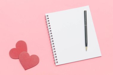 Sevgililer Günü için kalp şeklinde dekorasyonu olan boş bir defter ve kalem. Kopya alanı olan pembe arkaplan..