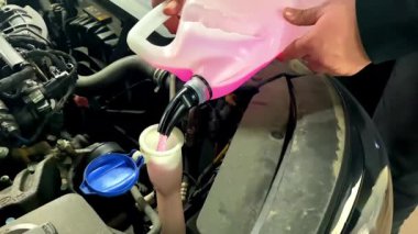 Sürücü antifriz dolduruyor, donmayan sıvı araba ön cam sileceği şişeyle yıkanıyor. Araba sezonluk ve makina. Sıvı cam cam temizleyici ya da kış sıvısı.