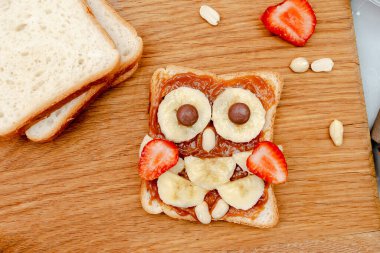Baykuş suratlı tost ekmeği. Fıstık ezmeli, çilekli. Komik çocuklar bebeğin tatlı tatlısını yiyor.
