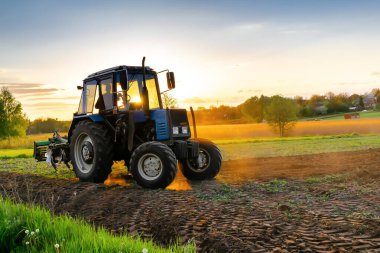 Tarlada tarla süren traktör makineleri. Çiftçi tarım yapıyor, ekin, ekin ekmeden önce toprak ekiyor, gün batımında kırsal alanda kırsal alanlarda ekiliyor..