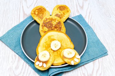 Çocuklar, çocuklar, tavşanlar, gözlemelerden tavşan, muz, tatlı şekerler, ahşap masa arkasında bal.