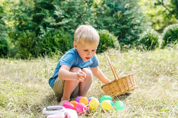 Paskalya yumurtası avı. Tavşan kulaklı küçük çocuk eğleniyor, çimenlerde yumurta topluyor. Paskalya bayramı geleneği..