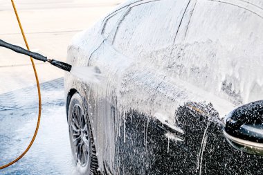 Yüksek basınçlı su jeti olan, otomatik oto yıkamada ekipman pompalı, köpüklü kimyasal deterjan kaplı bir araç.