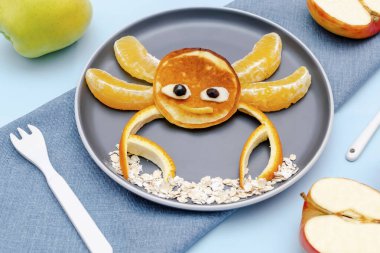 Krep, portakal, tabakta elma şeklinde komik yengeç suratlı atıştırmalıklar. Sevimli çocuklar bebekler tatlı tatlı tatlı tatlı tatlı, sağlıklı kahvaltı, öğle yemeği, mavi arka planda yemek sanatı, üst manzara.