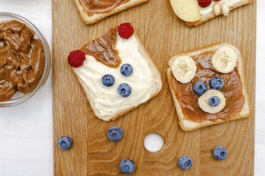Komik sevimli hayvanlar tost ekmeğine bakıyor. Çocuklar tatlı tatlı tatlı tatlı tatlı kahvaltılık sağlıklı yemek sanatı fıstık ezmesi, muz, yabanmersini, ahududu, üst manzara
