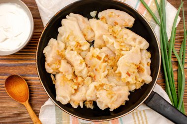 Hamur köftesi, vareniki, verenikli, haşlanmış lahanalı pirohy, paneldeki soğan. Geleneksel Ukrayna popüler yemeği, ahşap tahtada ekşi kremayla servis edilen mutfak..