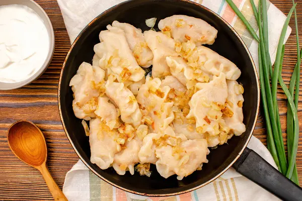 Hamur köftesi, vareniki, verenikli, haşlanmış lahanalı pirohy, paneldeki soğan. Geleneksel Ukrayna popüler yemeği, ahşap tahtada ekşi kremayla servis edilen mutfak..