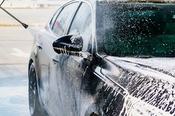 Yüksek basınçlı su jeti olan, otomatik oto yıkamada ekipman pompalı, köpüklü kimyasal deterjan kaplı bir araç.