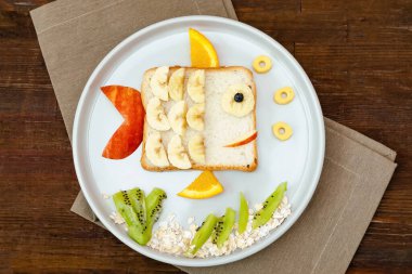 Komik, sevimli tost ekmeği. Çocuklar tatlıları, tatlıları sağlıklı öğle yemeği sanatı. Meyveli balık gibi, ahşap arka plan, üst manzara.
