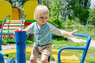 Şirin, komik, sarışın, küçük, çocuk çocuk çocuk. Çocuk parkında salıncakta sallanıyor, atlıkarıncaya biniyor. Fiziksel, duygusal gelişim, çocuk yuvası, anaokulu kavramı..