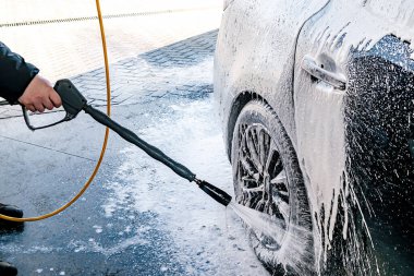 Yüksek basınçlı su jeti olan, otomatik oto yıkamada ekipman pompalı, köpüklü kimyasal deterjan kaplı bir araç.