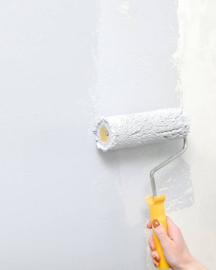 Duvarları gri fırçalı rulo ile boyamak, yaşamak, yatak odası, yeni bir daireye taşınmak. İç dekorasyon, bir apartman dairesinin tamiri..