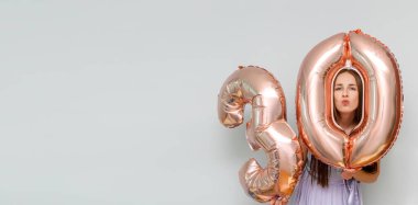 Mutlu genç yüzyıllık çekici kadın 30 numaralı balonları tutuyor, doğum gününü evde tatil partisinde kutluyor..