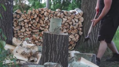 Siyah giyen adam ağır çekimde odun kesiyor, kereste topluyor.