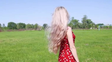 Kırmızı elbiseli kız uzun çimenlerde yürüyor, yaz tatili