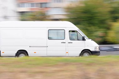 Beyaz minibüs şehir caddesinde hareket halinde.