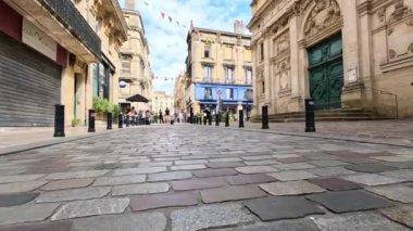 İnsanlar kaldırım taşlı bir sokakta yürüyor.