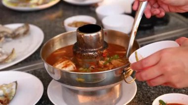 Elleri sıcak bir tencerede çorba servis ediyor.