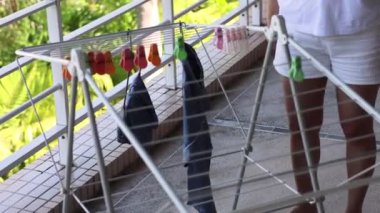 Dışarıdaki kurutma sehpasına kıyafet asan biri..