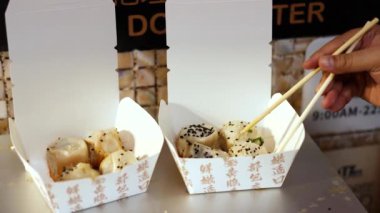 Dim sum toplamak için çubuk kullanıyor.