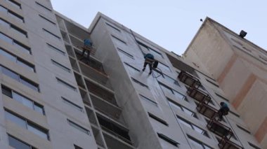Yüksek bir binanın camlarını temizleyen işçiler