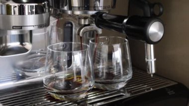 Espresso makinesi kahveyi iki bardağa dolduruyor.