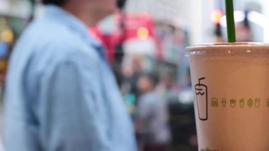 Kalabalık bir sokak sahnesi ve odaklanmış bir içecek.