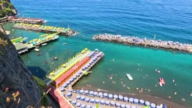 İnsanlar sahilde ve denizde eğleniyor.