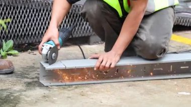 Metal kirişi kesmek için öğütücü kullanan işçiler