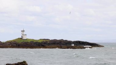 Dalgaların çarptığı kayalık adadaki deniz feneri