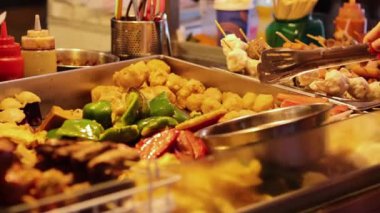 Satıcı yemek standında şiş hazırlıyor.