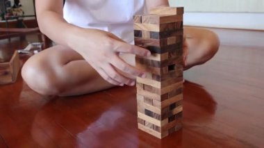 Jenga oynayan, blokları kaldıran ve istifleyen kişi.