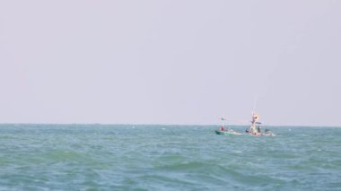 Dalgalı okyanus sularında küçük bir tekne hareket eder.