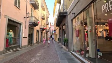 İnsanlar Alba, İtalya 'da dükkanların önünden geçiyor