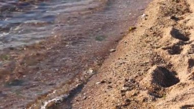 Dalgalar yavaşça kumlu ayak izlerini siler