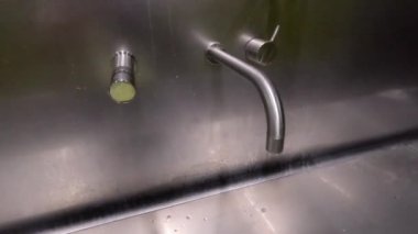 Paslanmaz çelik musluğu açan el.