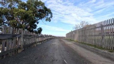 Ahşap çitli ve ağaçlı toprak yol