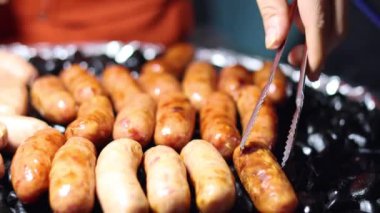 Sıcak ızgaranın üstünde sosis çeviriyorum.