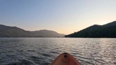 Sakin bir günbatımında bir kano gezisinin ilerlemesi
