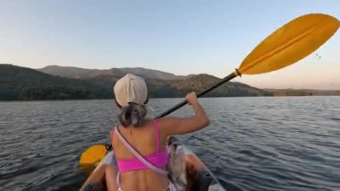 Huzurlu bir gölde kanoyla kürek çeken biri