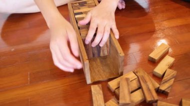 Eller oynuyor ve tahta Jenga kulesini deviriyor.