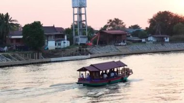Bir tekne alacakaranlıkta nehirden geçiyor.