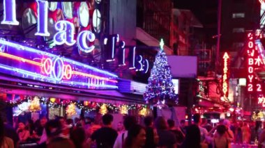 Neon ışıkları ve şenlikli süslemeleri olan kalabalık bir sokak.