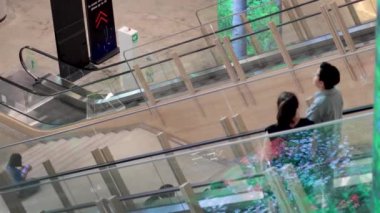 Yürüyen merdivenden birlikte inen iki kişi.