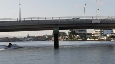 Sakin sular üzerinde bir köprünün altında jet ski hızlanıyor