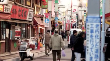 İnsanlar hareketli bir alışveriş caddesinde yürüyor.