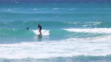 Bir sörfçünün dalga yakalaması ve sörf yapması.