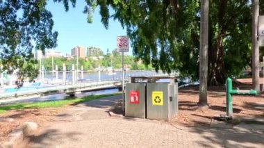 İnsanlar parkta çöp kutularının yanından geçiyorlar.