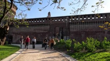İnsanlar Sforzesco Kalesi girişine doğru yürüyorlar.